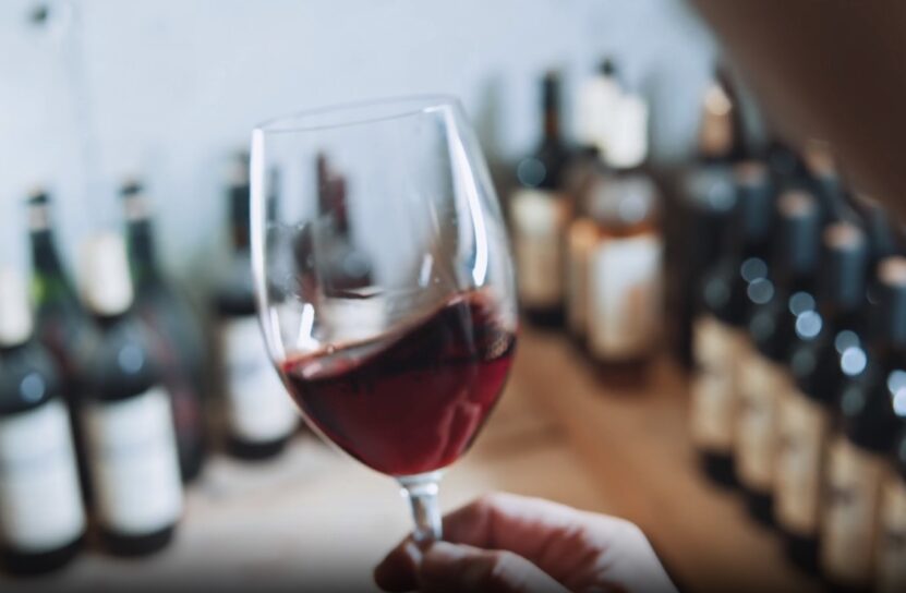 man holding wine glass, wines in the background